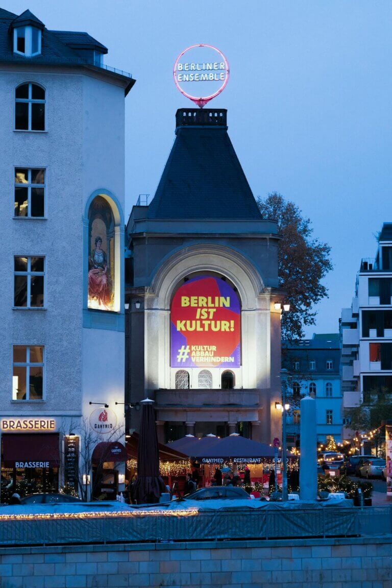 Evening view of Berliner Ensemble with vibrant 'Berlin ist Kultur' sign in Berlin, Germany.