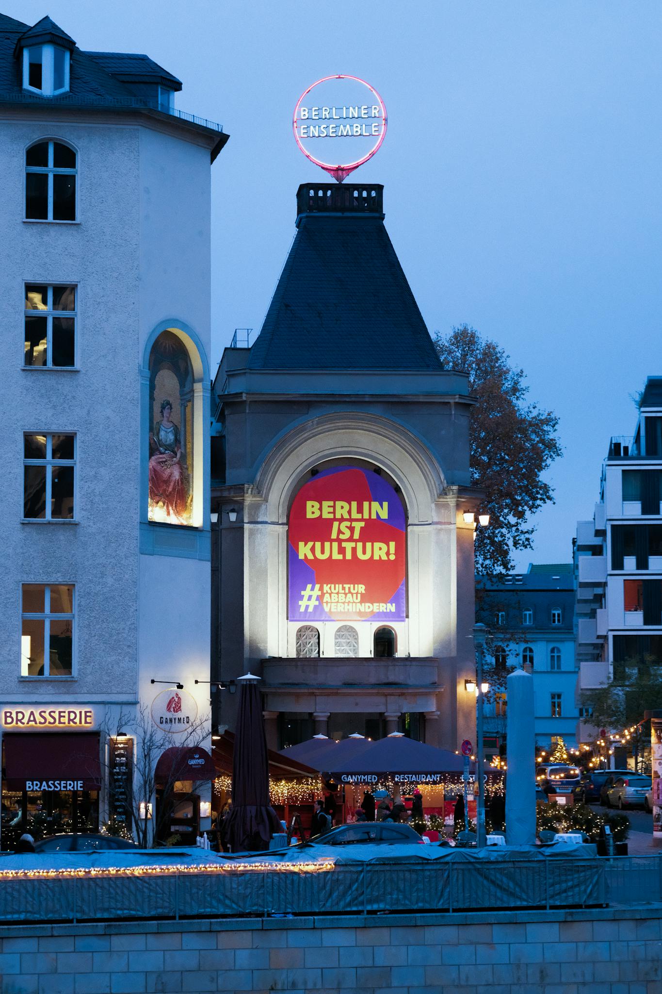 Evening view of Berliner Ensemble with vibrant 'Berlin ist Kultur' sign in Berlin, Germany.