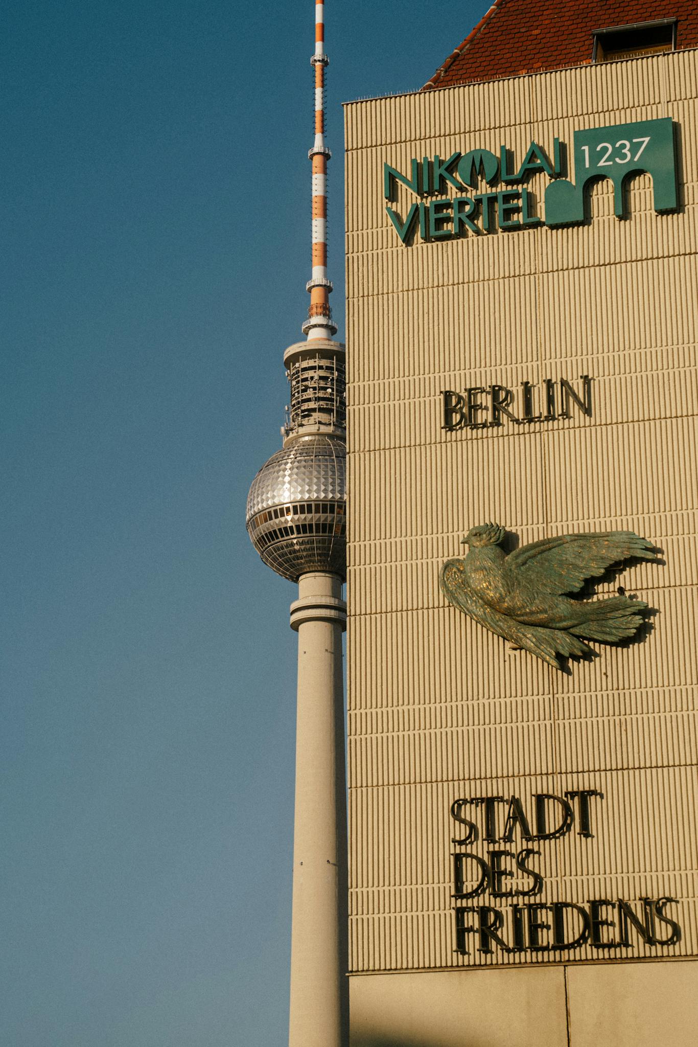 View of the Berlin TV Tower alongside wall art at Nikolaiviertel, showcasing iconic architecture.